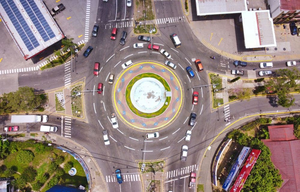 A roundabout keeping traffic flowing with no one directing each car: govern the road, not each journey